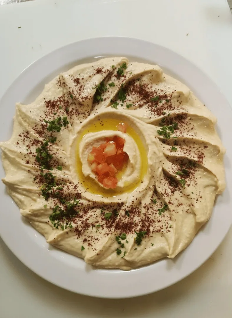 A bowl of creamy hummus drizzled with olive oil, served with warm pita at Mirage Mediterranean