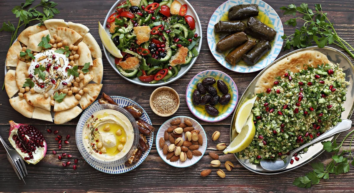 A large spread of Mediterranean dishes including hummus, tabbouleh, fattoush and mezze for catering